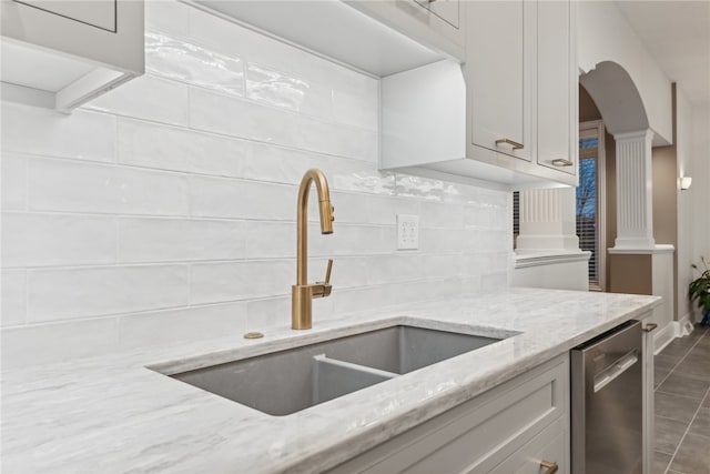 kitchen featuring dishwasher, sink, dark tile patterned floors, tasteful backsplash, and light stone counters