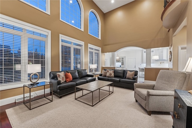 living room with wood-type flooring, a towering ceiling, and ornate columns