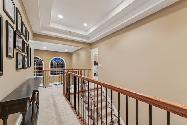 corridor featuring a tray ceiling and carpet floors