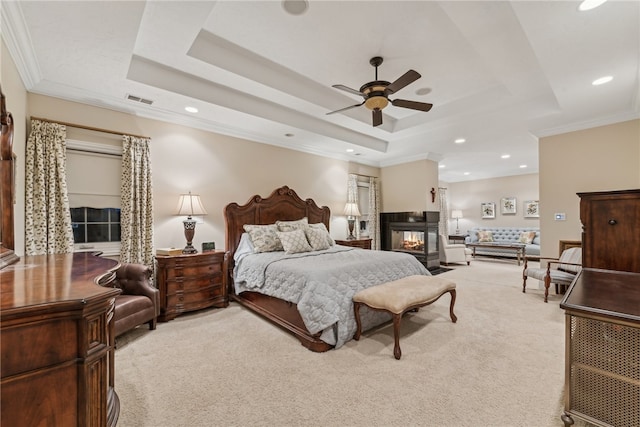 bedroom with a raised ceiling, light carpet, and ceiling fan