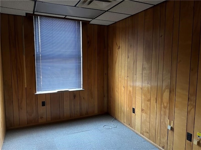 spare room with wood walls, a drop ceiling, and carpet floors