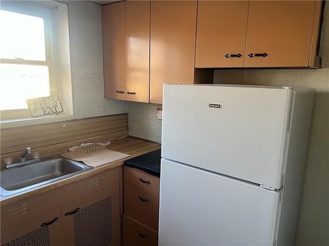 kitchen featuring decorative backsplash, sink, and white fridge