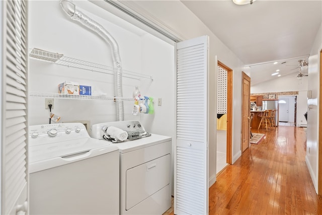 washroom with washing machine and clothes dryer and light hardwood / wood-style flooring