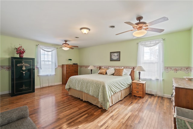 bedroom with ceiling fan, light hardwood / wood-style flooring, and multiple windows