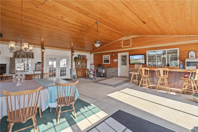 dining room featuring french doors, wooden ceiling, wood walls, vaulted ceiling, and ceiling fan with notable chandelier