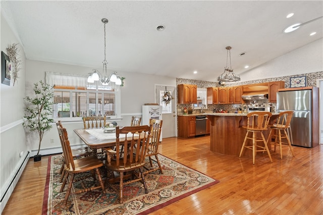 dining space with a chandelier, light hardwood / wood-style floors, lofted ceiling, and a baseboard heating unit