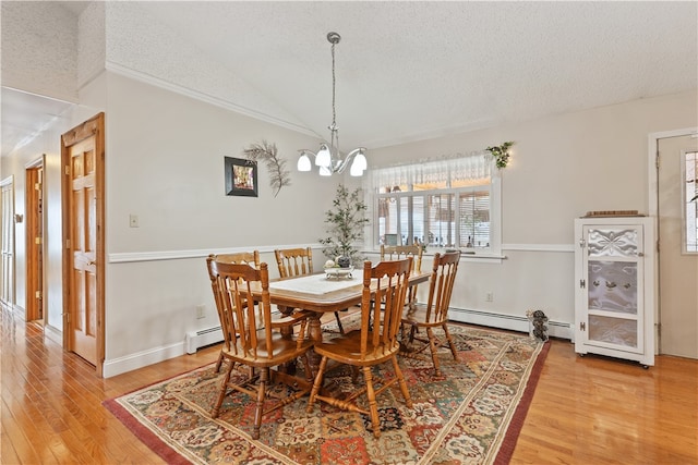 dining space featuring baseboard heating, a chandelier, lofted ceiling, a textured ceiling, and light wood-type flooring