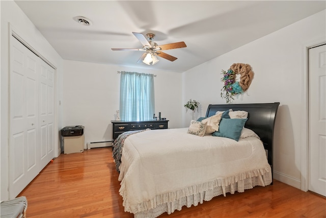 bedroom with hardwood / wood-style flooring, ceiling fan, a closet, and a baseboard heating unit