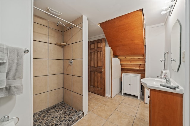 bathroom with a tile shower, wooden walls, tile patterned flooring, and vanity