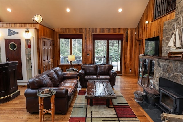 living room with wooden walls, light hardwood / wood-style floors, and lofted ceiling