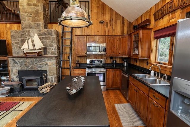 kitchen with wood walls, sink, stainless steel appliances, and dark hardwood / wood-style floors