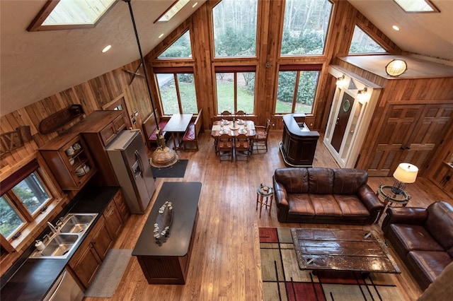 living room featuring a wealth of natural light, wooden walls, and high vaulted ceiling