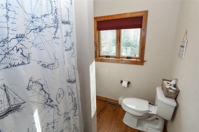 bathroom featuring hardwood / wood-style floors, toilet, and a shower with curtain