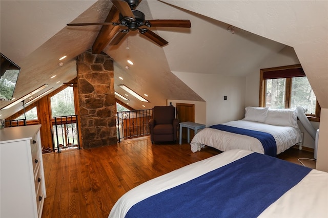 bedroom featuring multiple windows, lofted ceiling with skylight, ceiling fan, and dark hardwood / wood-style floors