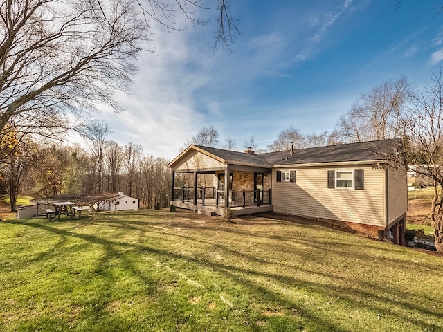 back of property with a yard, a wooden deck, and a sunroom