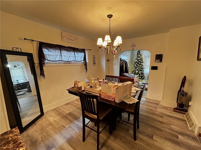 dining area featuring hardwood / wood-style flooring and an inviting chandelier