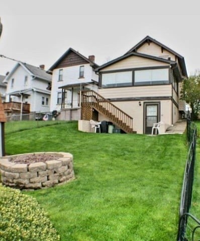 back of property featuring a lawn, a deck, and an outdoor fire pit