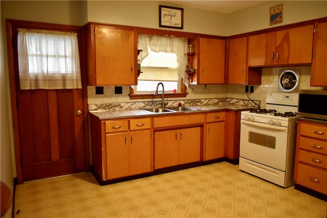 kitchen with backsplash, sink, white range with gas stovetop, and plenty of natural light