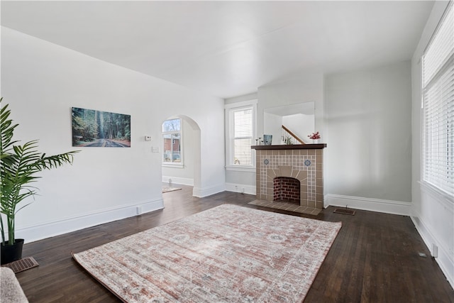 living room featuring a tile fireplace and dark hardwood / wood-style floors