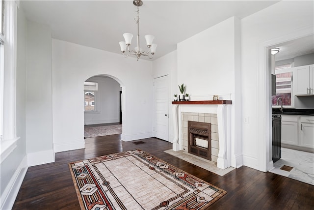 living room featuring dark hardwood / wood-style flooring, a tile fireplace, and a chandelier