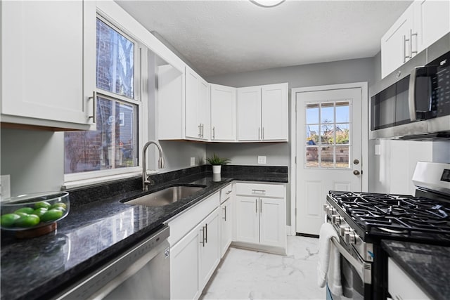 kitchen featuring white cabinetry, sink, dark stone counters, and appliances with stainless steel finishes