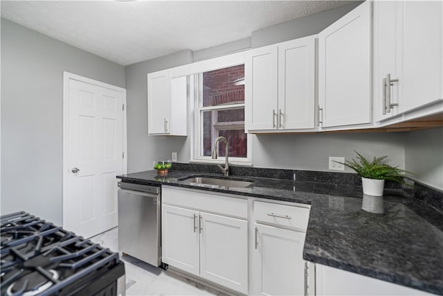 kitchen with white cabinets, stainless steel appliances, dark stone countertops, and sink