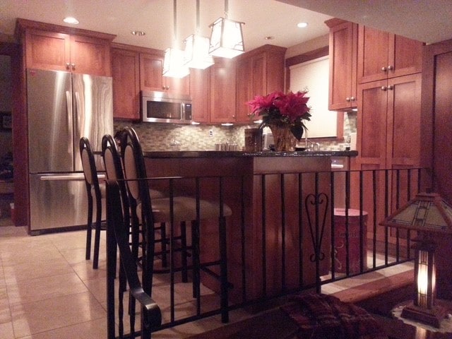 kitchen featuring hanging light fixtures, stainless steel appliances, a kitchen breakfast bar, backsplash, and kitchen peninsula