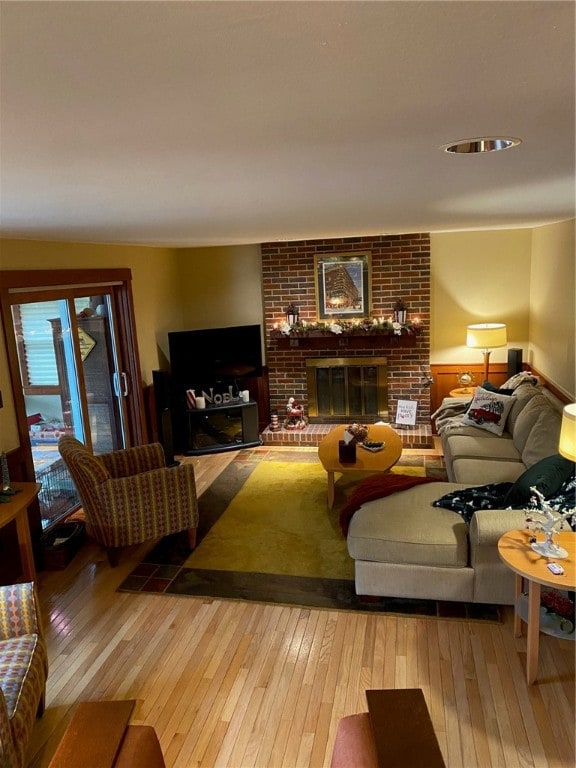 living room with wood-type flooring and a brick fireplace