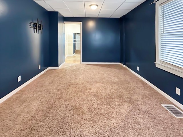 carpeted empty room with a drop ceiling