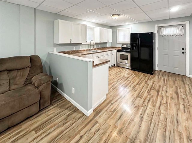 kitchen featuring stainless steel range with electric cooktop, black refrigerator with ice dispenser, sink, kitchen peninsula, and white cabinetry