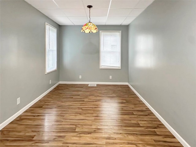 empty room featuring a paneled ceiling and hardwood / wood-style floors