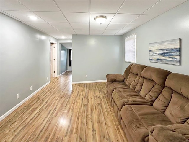 living room with a drop ceiling and light wood-type flooring