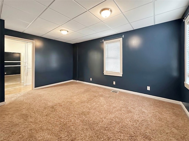 carpeted spare room featuring a drop ceiling