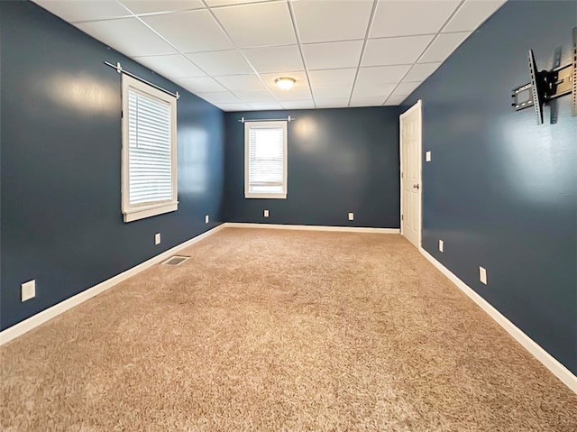 carpeted spare room featuring a drop ceiling