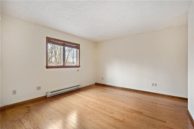 spare room featuring light wood-type flooring, a textured ceiling, and a baseboard heating unit