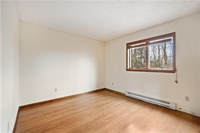 unfurnished room featuring light wood-type flooring, a textured ceiling, and a baseboard heating unit