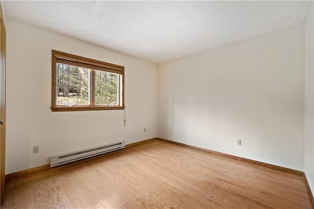 spare room featuring light wood-type flooring, a textured ceiling, and a baseboard heating unit