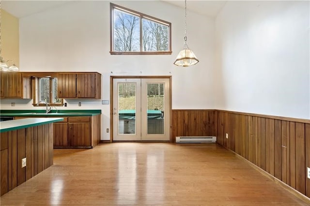 kitchen with high vaulted ceiling, pendant lighting, a baseboard radiator, and light wood-type flooring