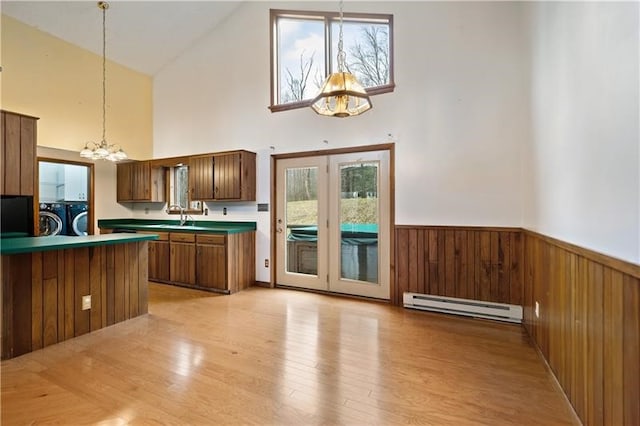 kitchen with independent washer and dryer, a baseboard radiator, high vaulted ceiling, and plenty of natural light