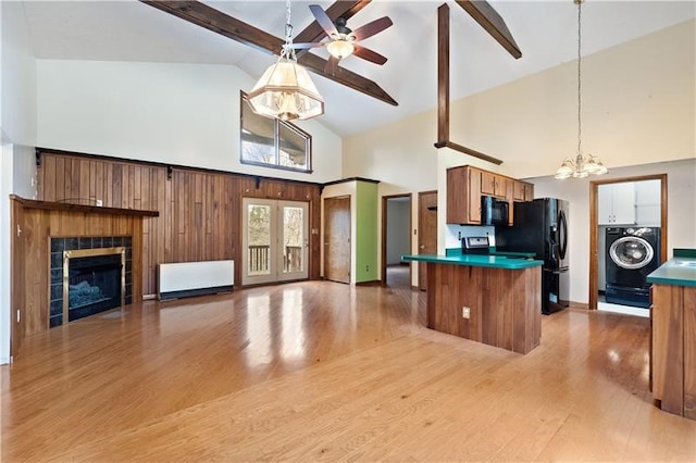 kitchen featuring beam ceiling, high vaulted ceiling, washer / clothes dryer, black appliances, and light wood-type flooring