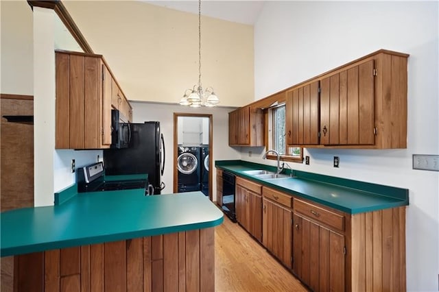 kitchen featuring light wood-type flooring, sink, a notable chandelier, independent washer and dryer, and hanging light fixtures