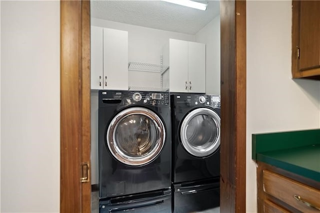 laundry room featuring cabinets, a textured ceiling, and washing machine and dryer