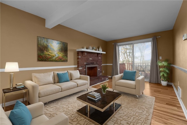 living room featuring beamed ceiling, wood-type flooring, and a brick fireplace