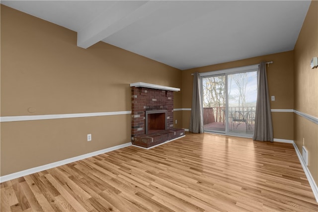 unfurnished living room with a fireplace, light wood-type flooring, and beamed ceiling