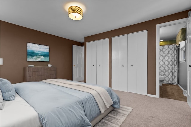 bedroom featuring carpet floors, two closets, and ensuite bath