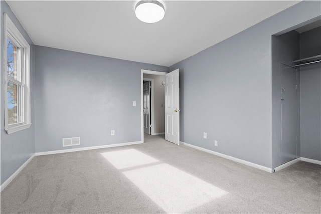 unfurnished bedroom featuring light carpet and a closet