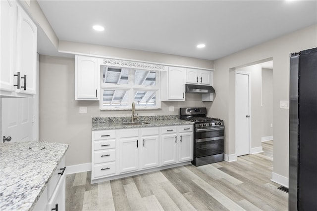 kitchen with white cabinets, stainless steel gas stove, light stone countertops, and sink