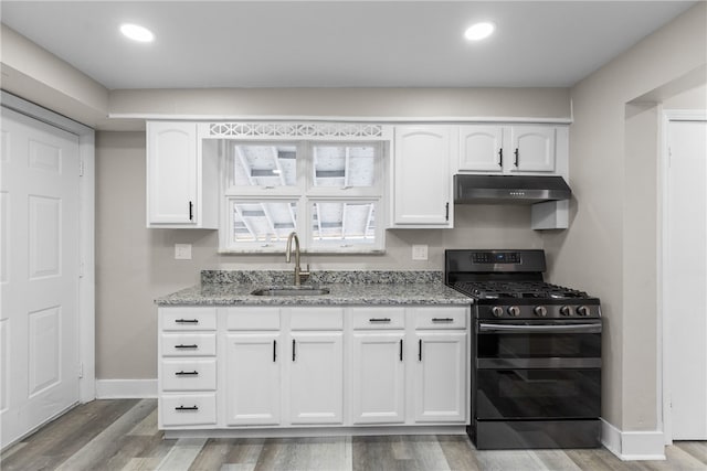 kitchen featuring sink, stainless steel gas range oven, light stone counters, hardwood / wood-style floors, and white cabinets