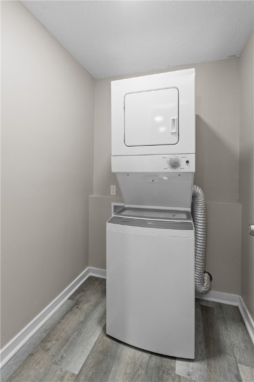 laundry area with stacked washer / drying machine and light hardwood / wood-style floors