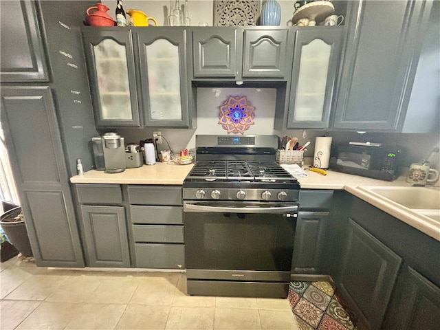 kitchen with light tile patterned floors, gas stove, and sink